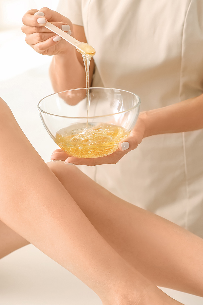 Schüsselchen mit Wachs als Vorbereitung für die Haarenetfernung an Damenbeinen